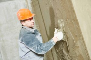 Construction worker plasterer with trowel plastering a wall