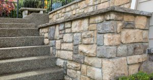 An exterior view of cultured stone being installed on the facade of a house in Edmonton, AB. The stones are being carefully aligned and attached with mortar, enhancing the home’s aesthetic and providing added protection against the elements.