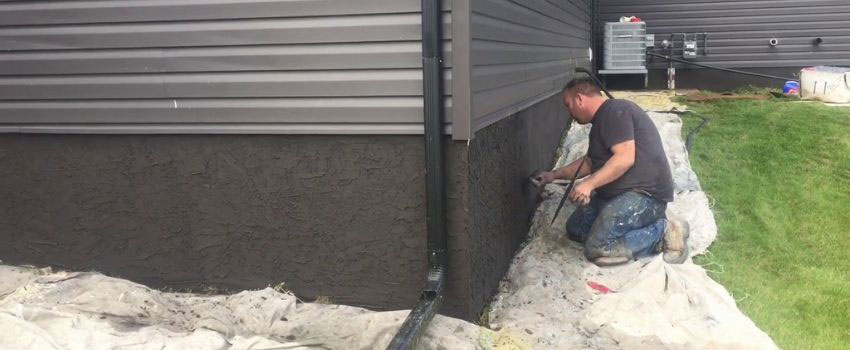 An image showing the EIFS (Exterior Insulation and Finish System) parging process on a home in Edmonton, AB. The installation involves applying a base coat and embedding fiberglass mesh over foam insulation boards to enhance strength and insulation.