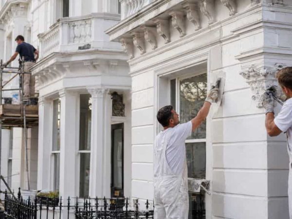 Contractors restoring white stucco and decorative masonry on a Victorian townhouse in Belgravia.