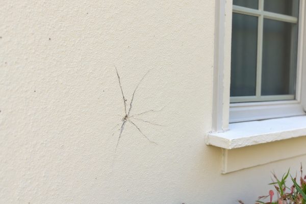 Hairline cracks in stucco near window caused by hail damage