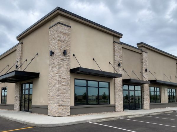 Depend Exteriors is a stucco contractor in Rutherford AB, Edmonton, providing exterior stucco services for commercial buildings. This image shows a modern building with beige stucco walls and stone column accents. The structure stands in a suburban area with a clean parking lot and overcast sky. You can call Depend Exteriors at (780) 710-3972 for stucco work in Rutherford and nearby Edmonton areas.