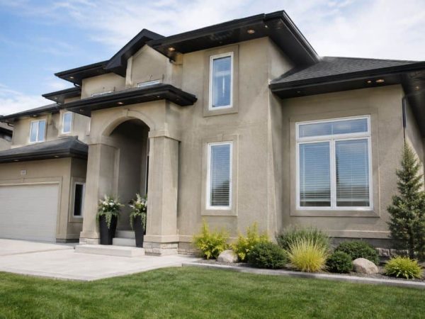 Finished two-storey home with textured stucco exterior, masonry accents, black rooflines, and landscaped front yard.