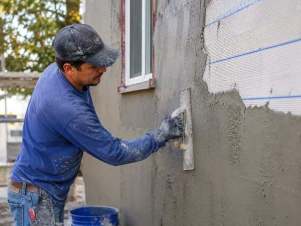 Contractor applying fresh stucco over reinforced exterior wall during a Hermitage home renovation.