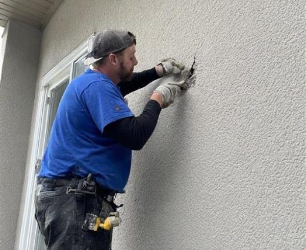 Windermere Edmonton Stucco Crack Repair Services Stucco crack repair on a residential home in Windermere, Edmonton, showing a technician sealing and blending a surface crack to prevent water intrusion and maintain exterior appearance.