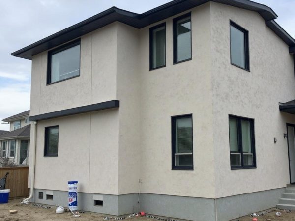 New two-storey home with clean white stucco exterior in Terwillegar AB, featuring smooth finish walls, dark window trims, and durable coating designed for Alberta weather by a local stucco contractor.